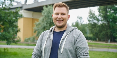 Nick, Azubi zum Gleisbauer, steht in einem Park vor einer Brücke