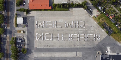 Viele BVG-Busse die aus Vogelperspektive den Schriftzug "weil wir dich lieben" bilden.