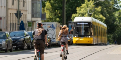 Ein Bild von zwei Fahrradfahrern vor einer Tram
