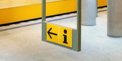 Blick auf ein Hinweisschild, das zur nächsten Kundeninformation weist.