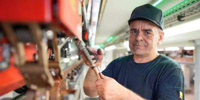 Fahrzeugelektriker Ralf wartet eine U-Bahn, die auf Gleisen in der Werkstatt aufgebockt ist.