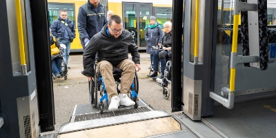 Eine Frau steigt mit einem Rollator in einen Bus.
