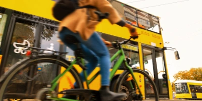 Eine Person fährt mit dem Fahrrad auf dem Radweg. Im Hintergrund fährt ein Bus.