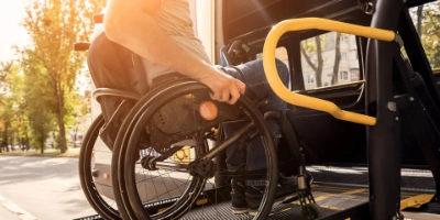Ein*e Mitarbeiter*in der BVG hilft einer Person im Rollstuhl in ein BVG Muva-Fahrzeug.