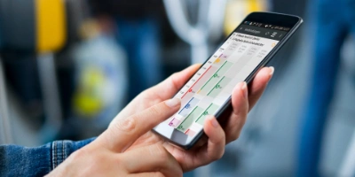 A hand holds a smartphone showing the Fahrinfo-App.