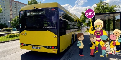Im Vordergrund ist Busti mit einer Gruppe von Kindern. Im Hintergrund ist ein Bus.