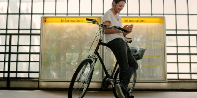 Mann steht mit seinem Fahrrad auf einem Bahnsteig und schaut in sein Handy.