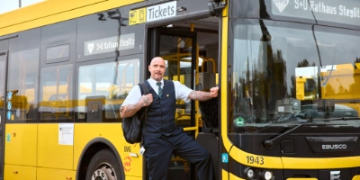 Ein Busfahrer steht an der Eingangstür mit Tasche
