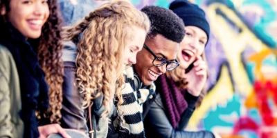 Auf dem Bild sind vier Jugendliche abgebildet. Sie unterhalten sich und lachen.