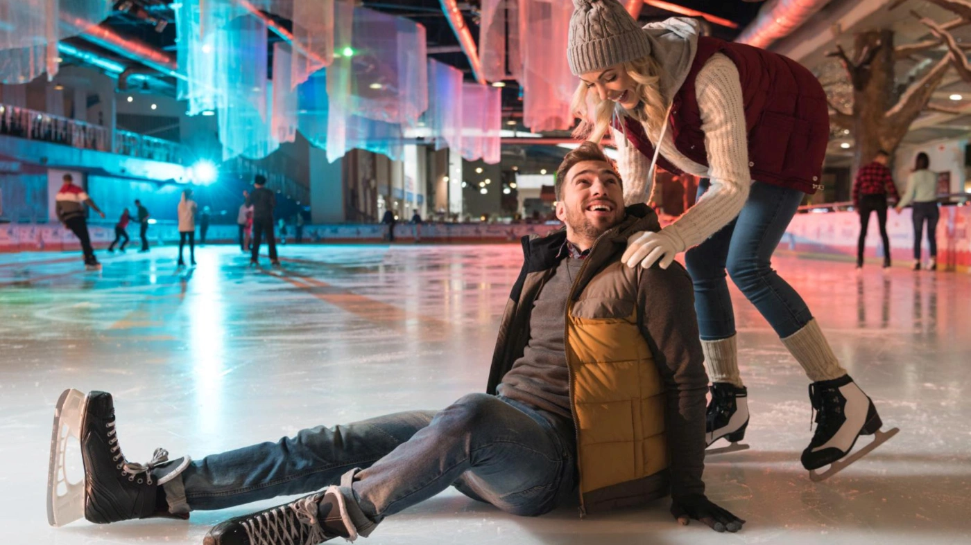 Ein Mann und eine Frau beim Schlittschuhfahren auf einer großen Eisfläche.