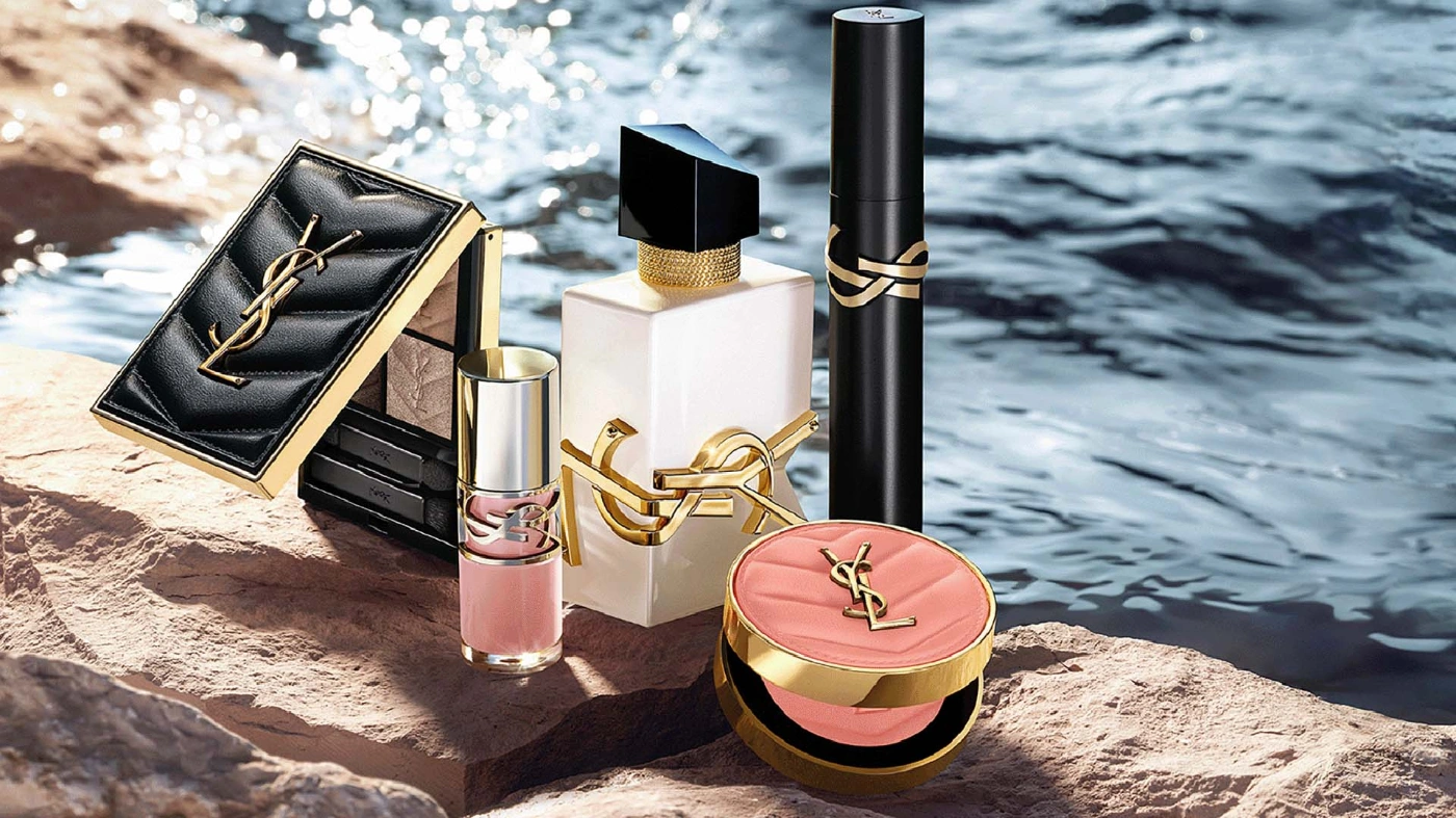 Zu sehen sind Produkte von Yves Saint Laurent. Sie stehen auf Steine und im Hintergrund ist ein Meer.