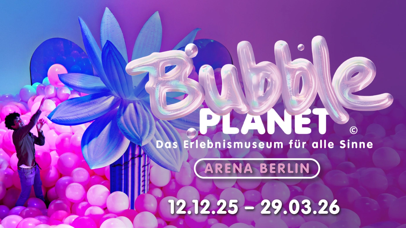 Hinter dem aus Ballons bestehenden Schriftzug "Bubble Planet" steht eine Person inmitten von pinken Luftballons vor einer aufgeblasenen blauen Blume, die riesig wirkt. 