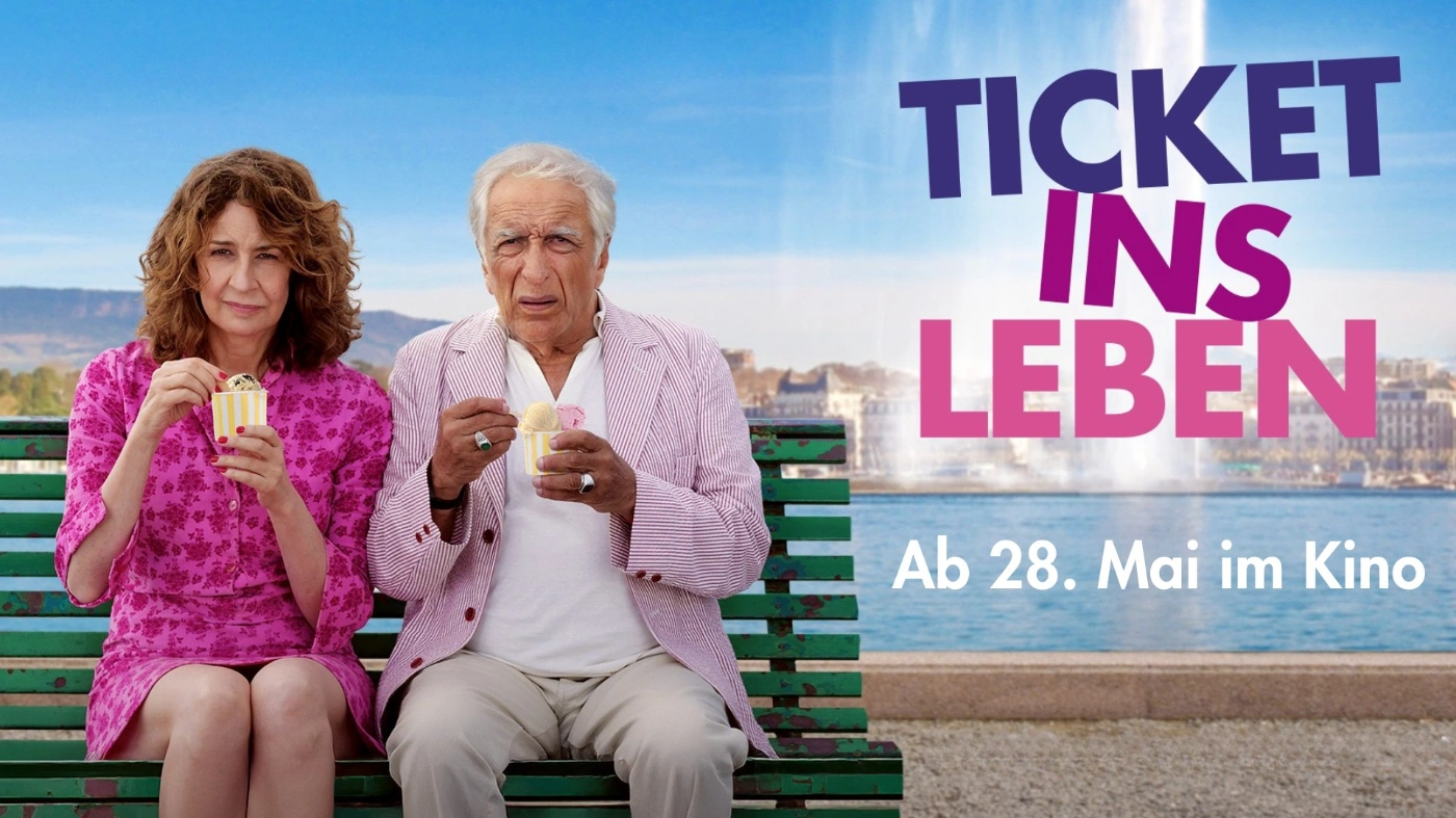 Zu sehen ist ein Kinoplakat zu „Ticket ins Leben“. Eine Frau im pinken Kleid und ein älterer Mann im hellen Jackett sitzen mit Eisbechern auf einer grünen Bank vor einem See mit Springbrunnen. Rechts steht der Filmtitel „TICKET INS LEBEN“ sowie der Hinweis „Ab 28. Mai im Kino“.