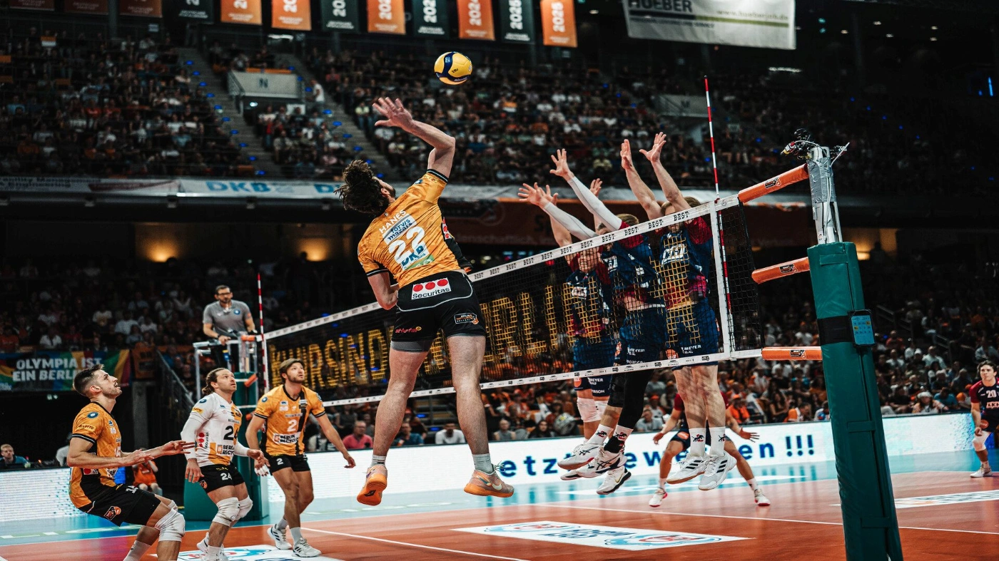 Eine Mannschaft in orangen Trikots spielt gegen eine andere Mannschaft in schwarzen Trikots Volleyball in der Max-Schmeling-Halle.