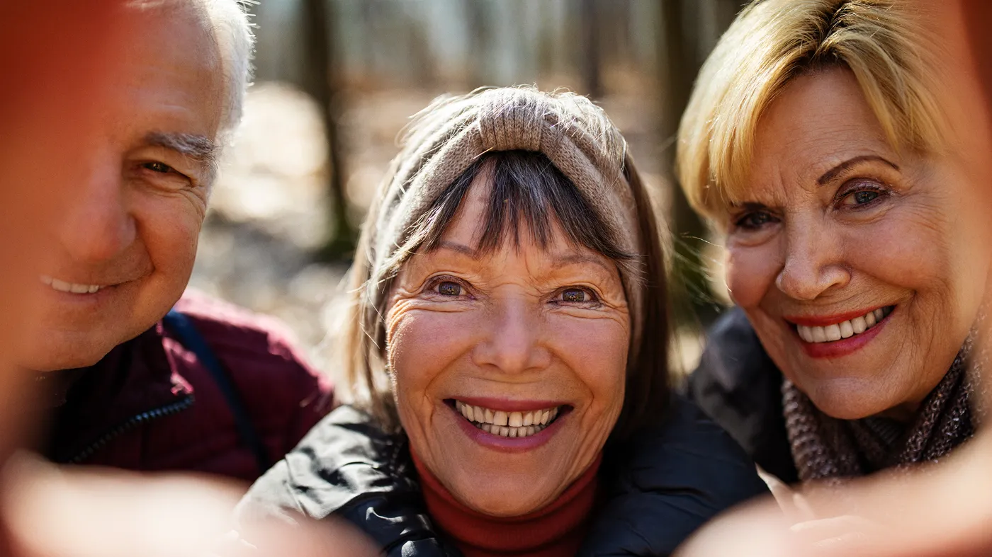 Two older women and a senior citizen laugh into the camera.