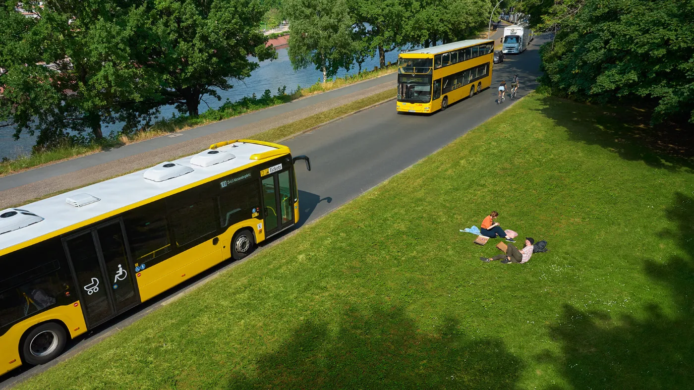 Zwei Busse der BVG fahren an einem Park vorbei