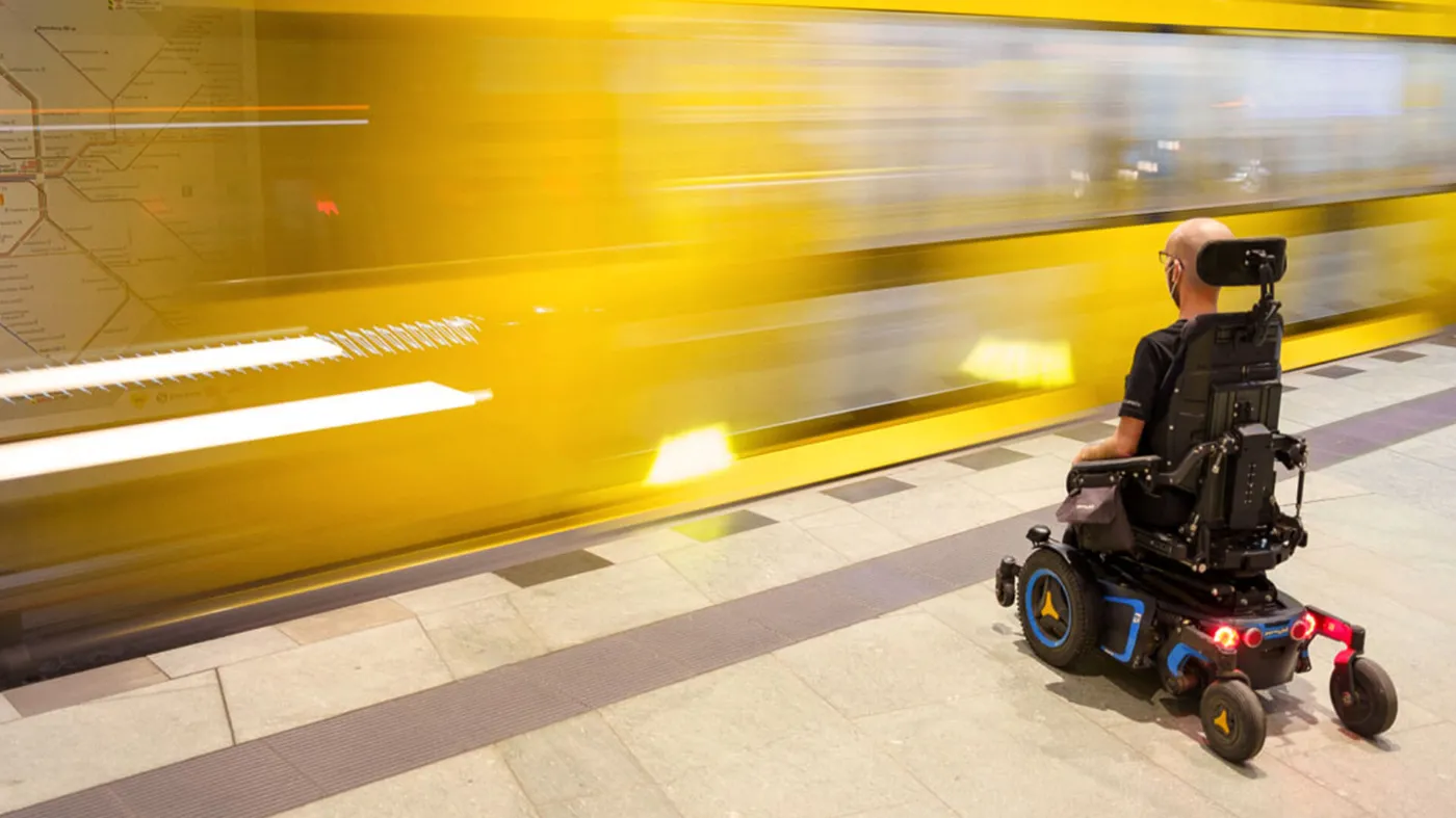 Ein Rollstuhlfahrer wartet am Bahnsteig auf eine einfahrende U-Bahn. 