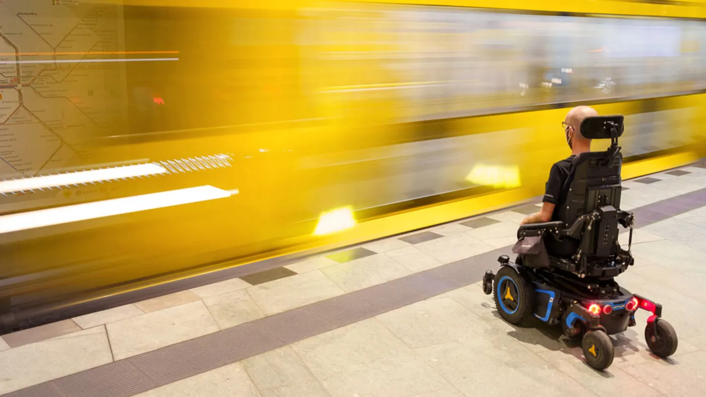 Ein Rollstuhlfahrer wartet am Bahnsteig auf eine einfahrende U-Bahn.
