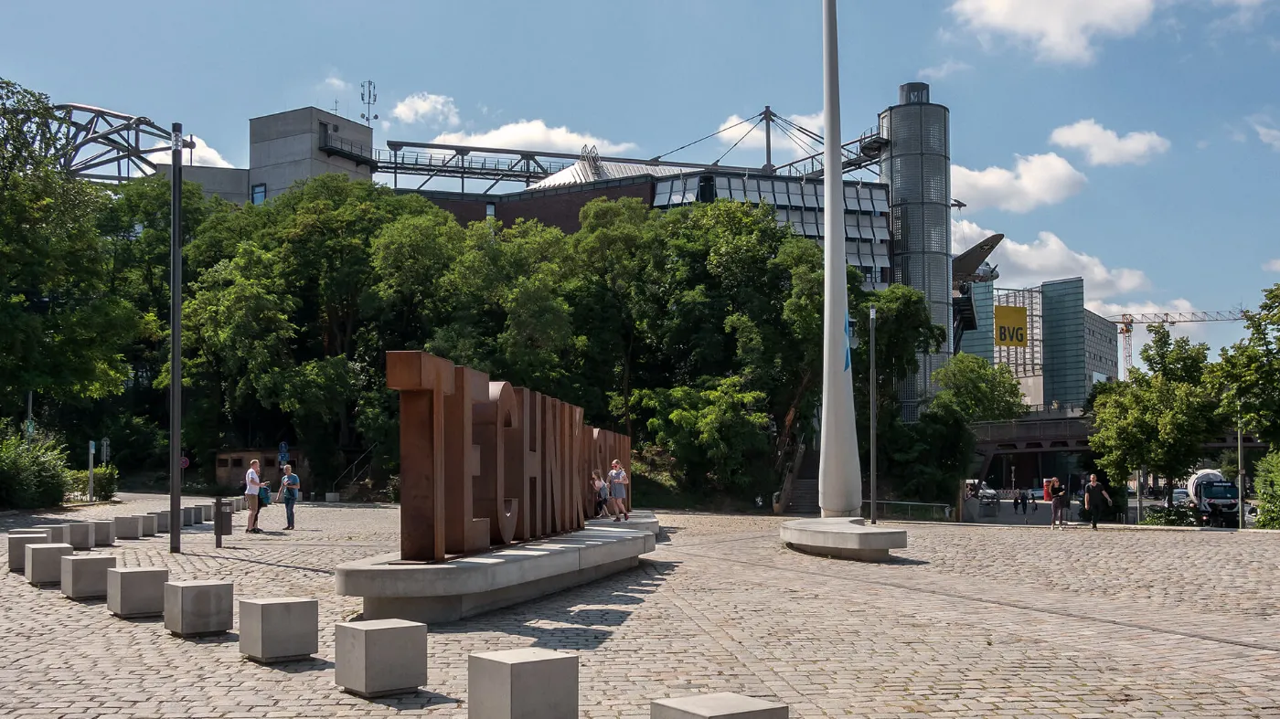 Der Platz vor dem Technikmuseum im Sonnenschein. Zu sehen sind große Betonbuchstaben, die auf dem Vorplatz das Wort "Technikmuseum" bilden. 