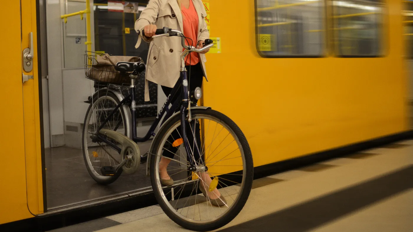 A woman pushes her bicycle out of a subway.