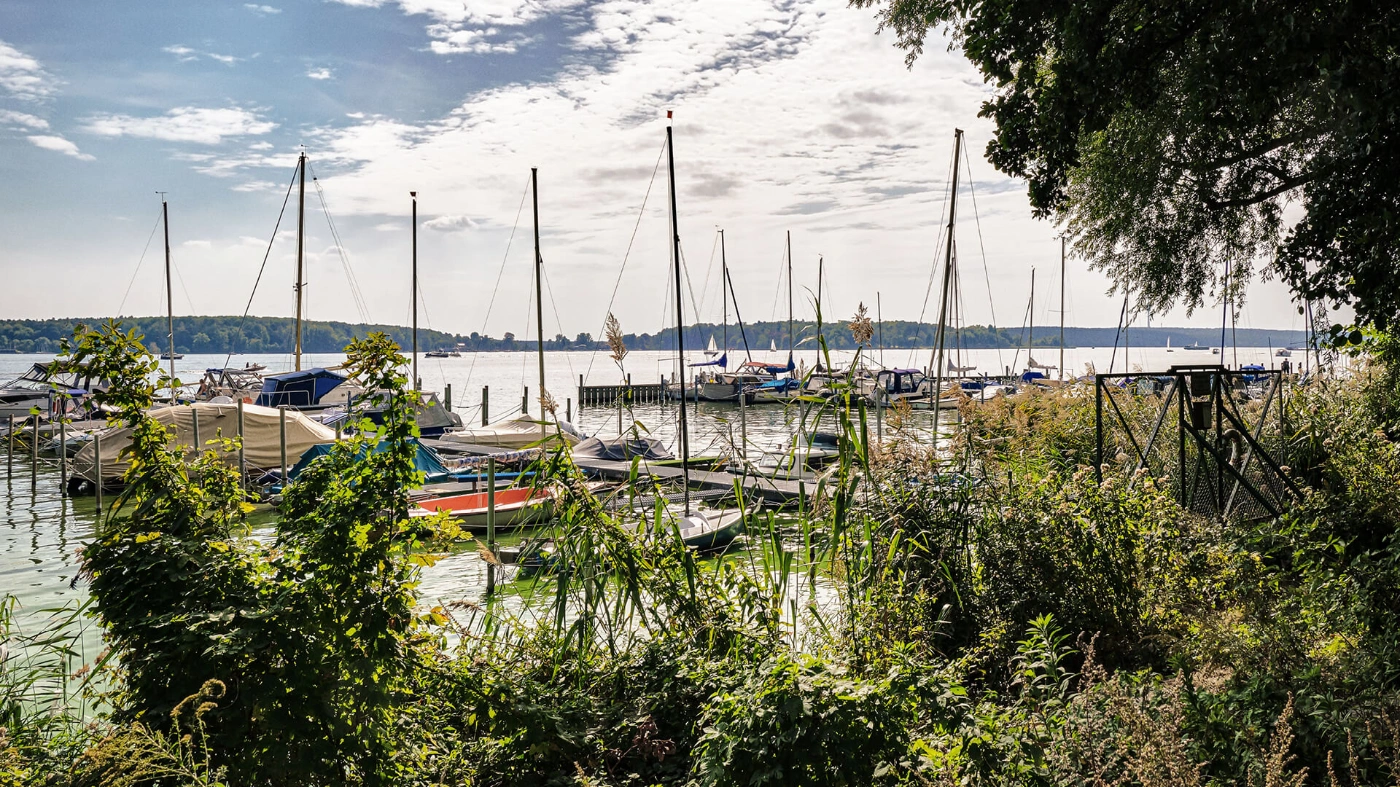 Zu sehen ist der Blick auf die Havel. Dort liegen einige Segelboote an einem kleinen Hafen.