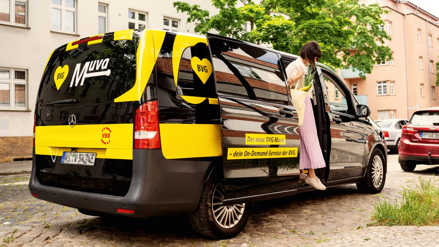 Eine junge Frau steigt aus einem parkenden BVG Muva. 