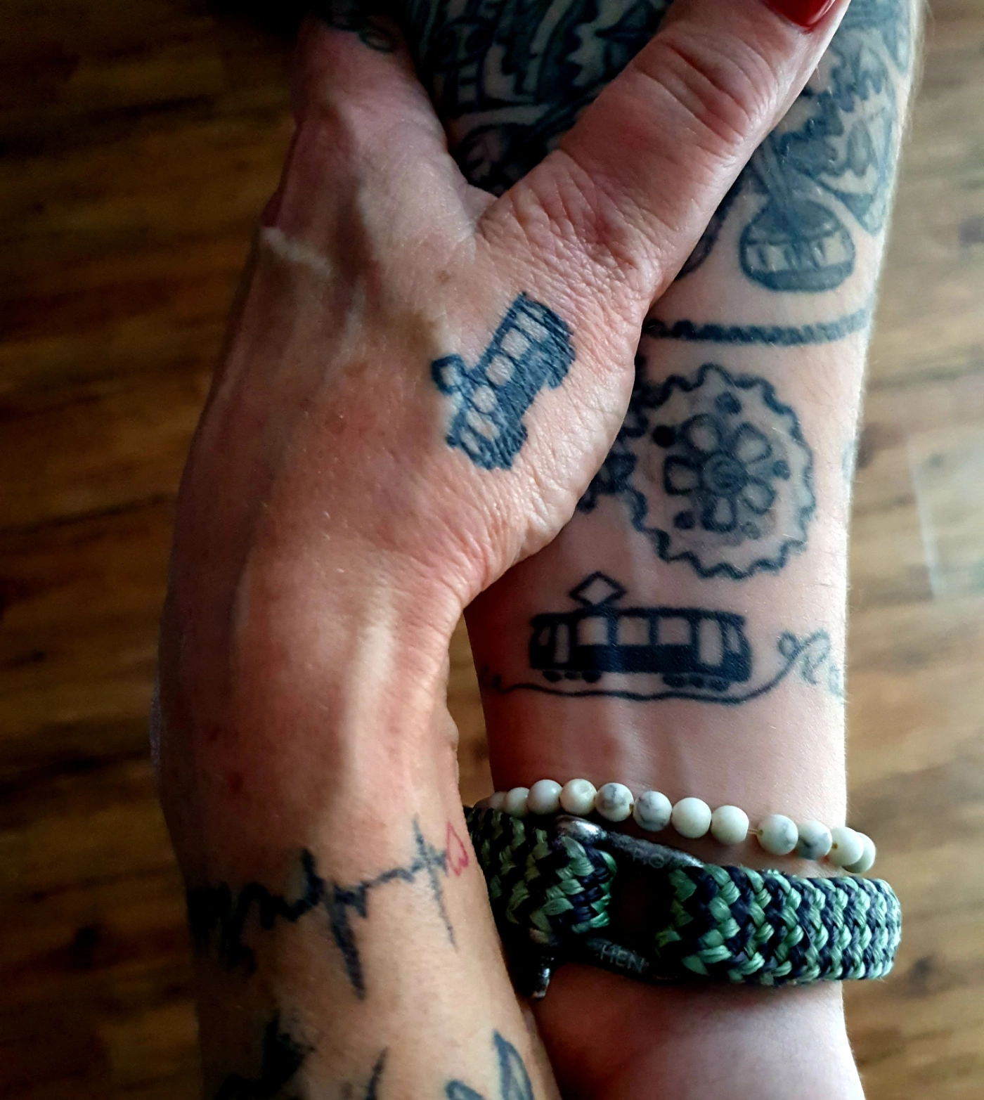 Nahaufnahme, wie Mutter und Tochter ihr Hände halten, mit Blick auf die BVG-Tattoos auf beiden Armen.