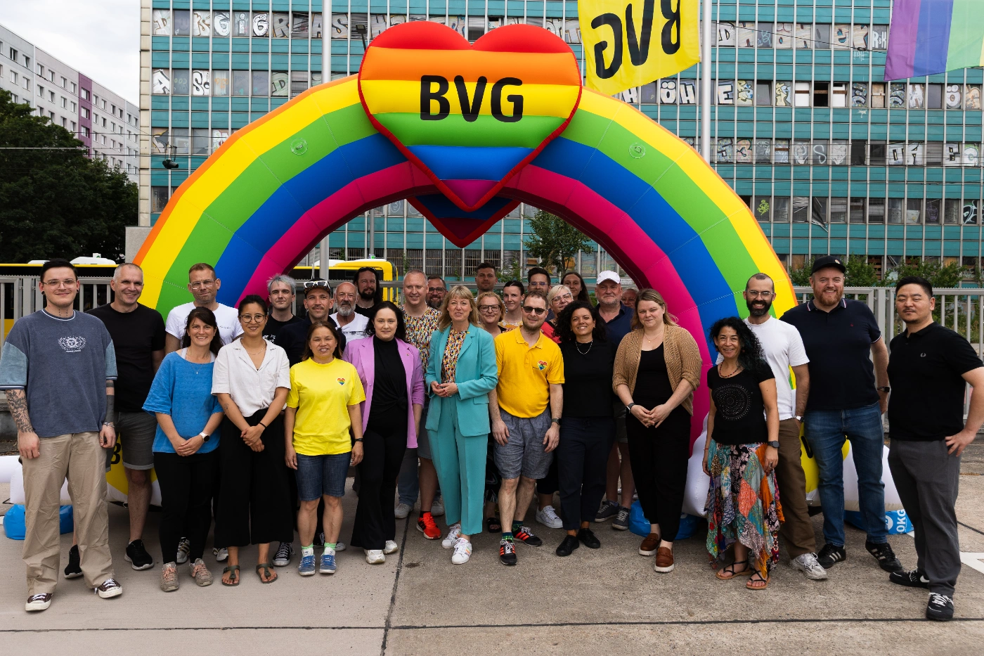 Viele Personen stehen vor einem bunten Regenbogen mit einem bunten BVG-Herz.