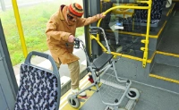 A woman gets on a bus with a walker.