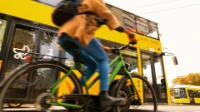 Eine Person fährt mit dem Fahrrad auf dem Radweg. Im Hintergrund fährt ein Bus.