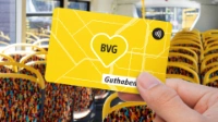 Eine Person hält die BVG Guthabenkarte in die Kamera und steht dabei in einem Bus. 