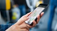 A hand holds a smartphone showing the Fahrinfo-App.