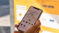 A hand holds a smartphone on which the Jelbi app can be seen.