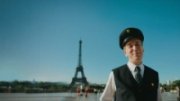 Ein BVG-Mitarbeiter steht vor dem Eiffelturm in Paris und blickt lächelnd in die Kamera. Im Hintergrund sind der Eiffelturm, eine Parkanlage und der Pariser Stadtblick zu sehen.
