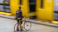 Eine Frau steht neben ihrem Fahrrad, während sie auf eine einfahrende U-Bahn wartet.