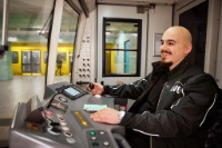 Ein BVG-Auszubildender sitzt im Fahrstand einer U-Bahn, trägt Uniform und blickt konzentriert auf die Strecke – Symbolbild für die Ausbildung zur Fachkraft im Fahrbetrieb.