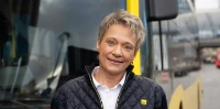 Portraitfoto: Simone steht in BVG-Dienstkleidung für Fahrerinnen vor einem BVG Bus