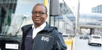 Busfahrer Salem steht in BVG-FAhrdienstkleidung vor einem Bus