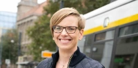 Straßenbahnfahrerin Susan steht vor einer Straßenbahn