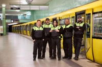 Fünf Mitarbeitende aus dem Sicherheitsdienst stehen vor einer U-Bahn.