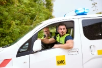 Zwei Sicherheitsmitarbeiter in Arbeitskleidung sitzen in einem BVG-Transporter und halten Ausschau.