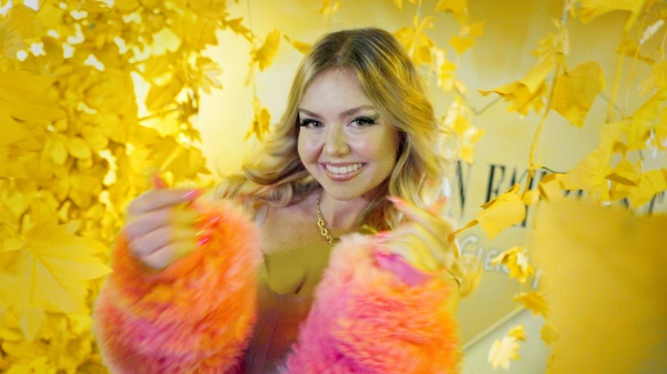 Candy, Kandidatin für IBEF, strahlt in die Kamera: Sie hat blonde lange Haare, lange pinke Fingernägel und trägt eine pinke Felljacke.