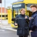 Zwei Personen aus dem Fahrdienst unterhalten sich, im Hintergrund sieht man einen E-Bus.